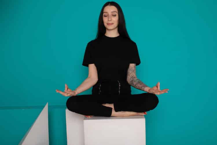 Beautiful young woman sitting in yoga position and meditating i