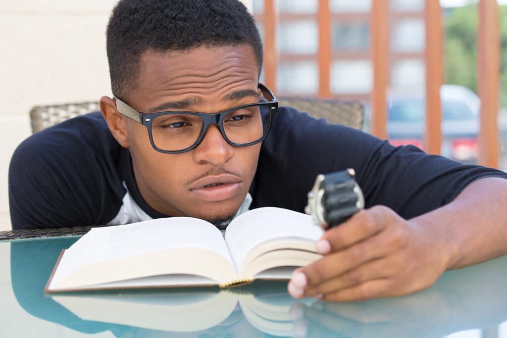 male student looking at watch and book